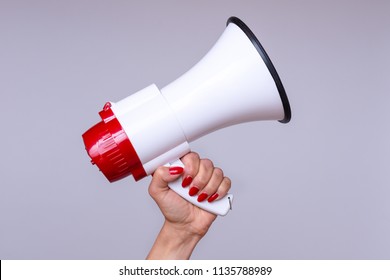Woman holding up a loud hailer, bullhorn or megaphone as she prepares to stage a protest or demonstration to air her grievances - Shutterstock ID 1135788989