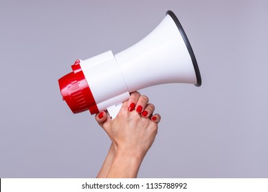 Woman holding up a loud hailer, bullhorn or megaphone as she prepares to stage a protest or demonstration to air her grievances - Shutterstock ID 1135788992