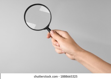 Woman holding magnifying glass on grey background, closeup. Find keywords concept - Powered by Shutterstock