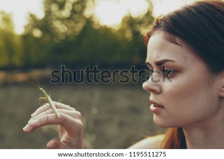 woman holding a mantis on her hand against the background of nature                         