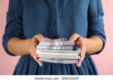 Woman holding many different handkerchiefs against pink background, closeup