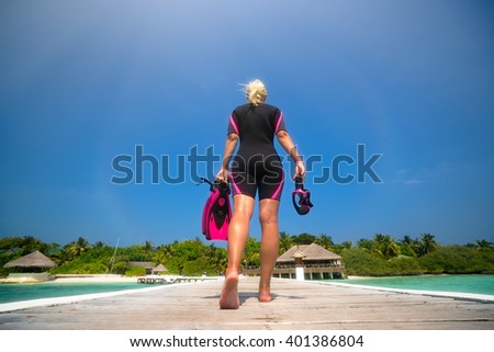 Woman holding mask and flippers for swimming on the background the beach