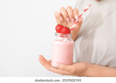 Woman holding mason jar of tasty strawberry smoothie on light background - Powered by Shutterstock