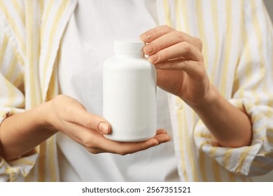 Woman holding medical bottle with pills, closeup