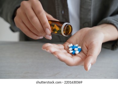 Woman holding medicine bottle pour pills into palm to take dietary supplements, vitamins or medicines, close up of female taking painkiller or sleeping tablets. Health care and wellness - Shutterstock ID 2201630369