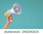 Woman holding megaphone speaker on blue background, closeup. Space for text