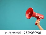 Woman holding megaphone speaker on blue background, closeup. Space for text