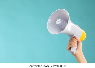 Woman holding megaphone speaker on blue background, closeup. Space for text