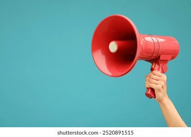 Woman holding megaphone speaker on blue background, closeup. Space for text