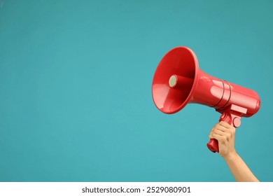 Woman holding megaphone speaker on blue background, closeup. Space for text