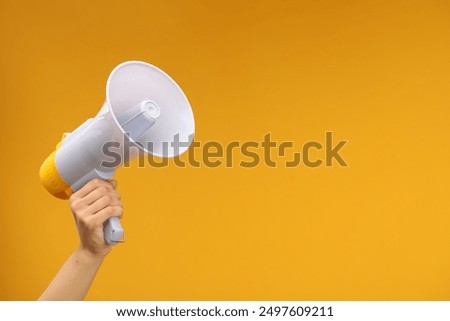 Woman holding megaphone speaker on orange background, closeup. Space for text