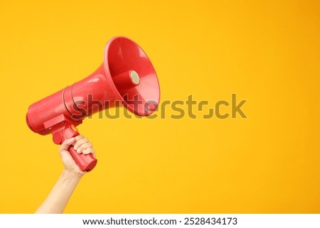 Woman holding megaphone speaker on orange background, closeup. Space for text