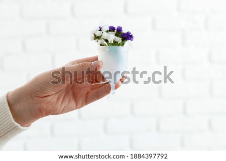 Woman holding menstrual cup with flowers close up