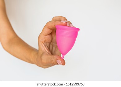 woman holding menstrual cup on white background. Feminine hygiene alternative product instead of tampon during period. Menstruation, critical days, women periods. Zero waste, eco, ecology.