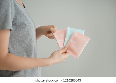 Woman Holding Menstrual Pads On Grey Background