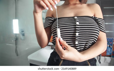 Woman Holding Menstrual Tampon At Bathroom.