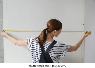 Woman holding a meter, measuring dimensions on plasterboard panel - DIY home improvement concept
 - Powered by Shutterstock