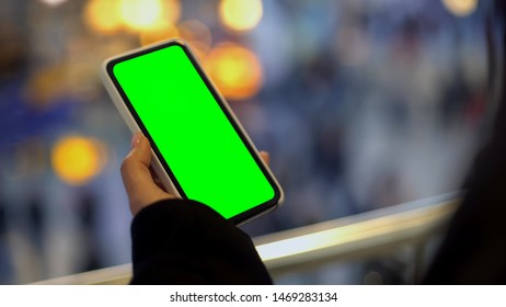 Woman Holding Mobile Phone With Green Screen, Standing In Shopping Center, Ad