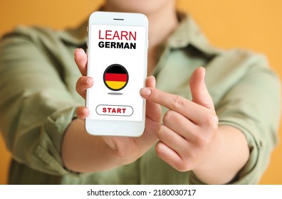 Woman Holding Mobile Phone With Text LEARN GERMAN On Screen, Closeup