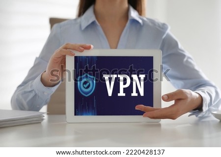 Woman holding modern tablet with switched on VPN indoors, close up