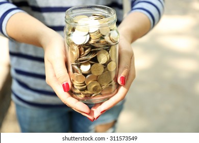 Woman Holding Money Jar With Coins Outdoors