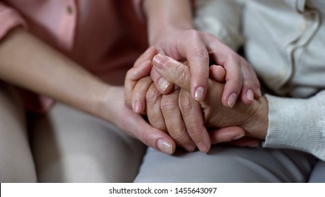 Woman holding mother hands closeup, nursing home support, family love and help
