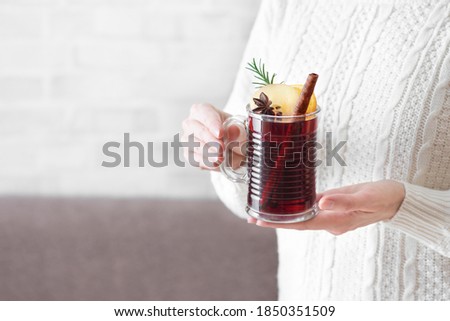 Woman holding mug of hot mulled wine, copy space. Female hands with cup of seasonal winter hot drink. Homemade fruit Christmas drink, spicy mulled red wine.