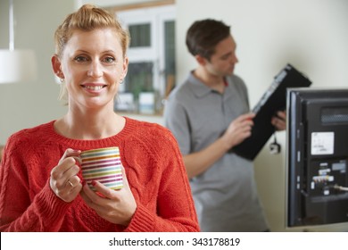 Woman Holding Mug Whilst Engineer Installs TV Equipment