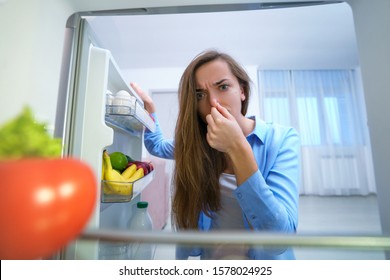 Woman Holding Nose Due To Bad Unpleasant Smell From Spoiled Food In The Refrigerator