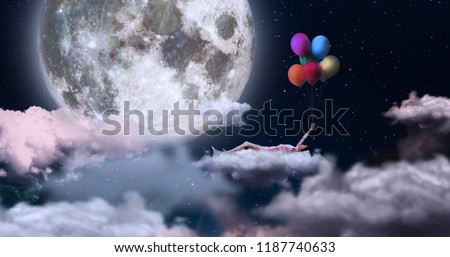 A woman holding on to colored balloons, flying in the sky lying on a cloud. On the sfin a giant moon. Concept of: dreams, freedom.