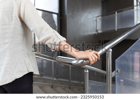 woman holding on to the handrail in the passage. woman climbing the stairs holding on to the railing. 