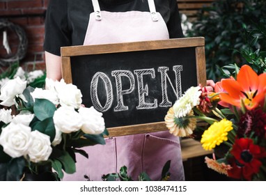 Woman holding open sign among flowers bouquet on florist shop - Powered by Shutterstock