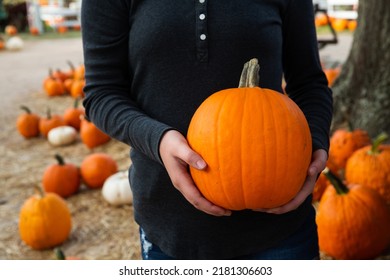 Woman Holding Orange Pumpkin Gourd At Local Fall Festival Pumpkin Patch With Room For Copy Space On Pumpkin.