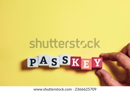 Woman holding painted colorful wooden blocks with the inscription Passkey on yellow background. New safer security system for digital devices.