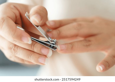 A woman is holding a pair of nail clippers and smiling. Concept of relaxation and self-care, as the woman is taking the time to groom her nails