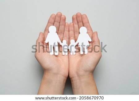 Woman holding paper family cutout on light grey background, top view
