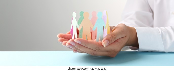 Woman holding paper human figures at table, closeup. Diversity and Inclusion concept - Shutterstock ID 2174511967