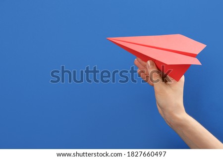 Woman holding paper plane on blue background, closeup. Space for text