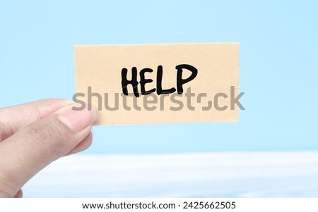 Woman holding paper spelling words HELP with blue background. Torn piece of paper with the word 