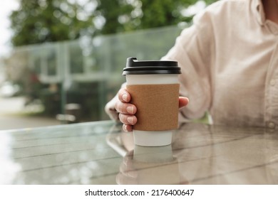 Woman Holding Paper Takeaway Cup At Glass Table Outdoors, Closeup. Coffee To Go