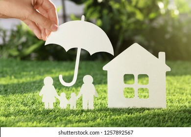 Woman holding paper umbrella over cutout of family and house on fresh grass, closeup. Life insurance concept - Powered by Shutterstock