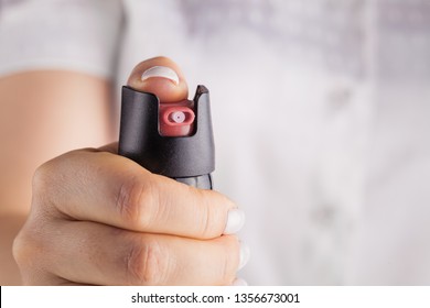 Woman holding pepper spray (tear gas) in his hand. Self defense. Blur background, close up