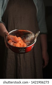 Woman Holding A Pet Bowl With Raw Trout In Hand. Rustic Style. Vertical.