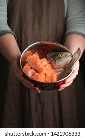 Woman Holding A Pet Bowl With Raw Trout In Hand. Rustic Style. Vertical.