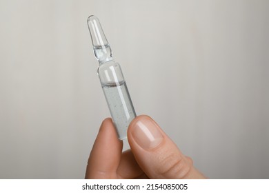 Woman Holding Pharmaceutical Ampoule With Medication On White Background, Closeup