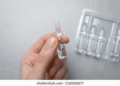 Woman Holding Pharmaceutical Ampoule With Medication At Light Grey Table, Top View