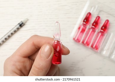 Woman Holding Pharmaceutical Ampoule With Medication At White Wooden Table, Top View