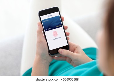 woman holding phone with debit card app touch pay on screen 