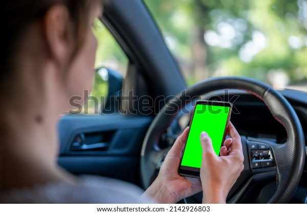 Woman holding a phone with\
green screen in the car. business woman sitting with phone in\
car.