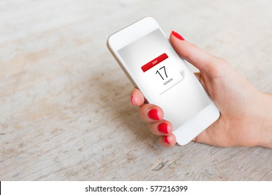 Woman holding phone in hand and looking at calendar